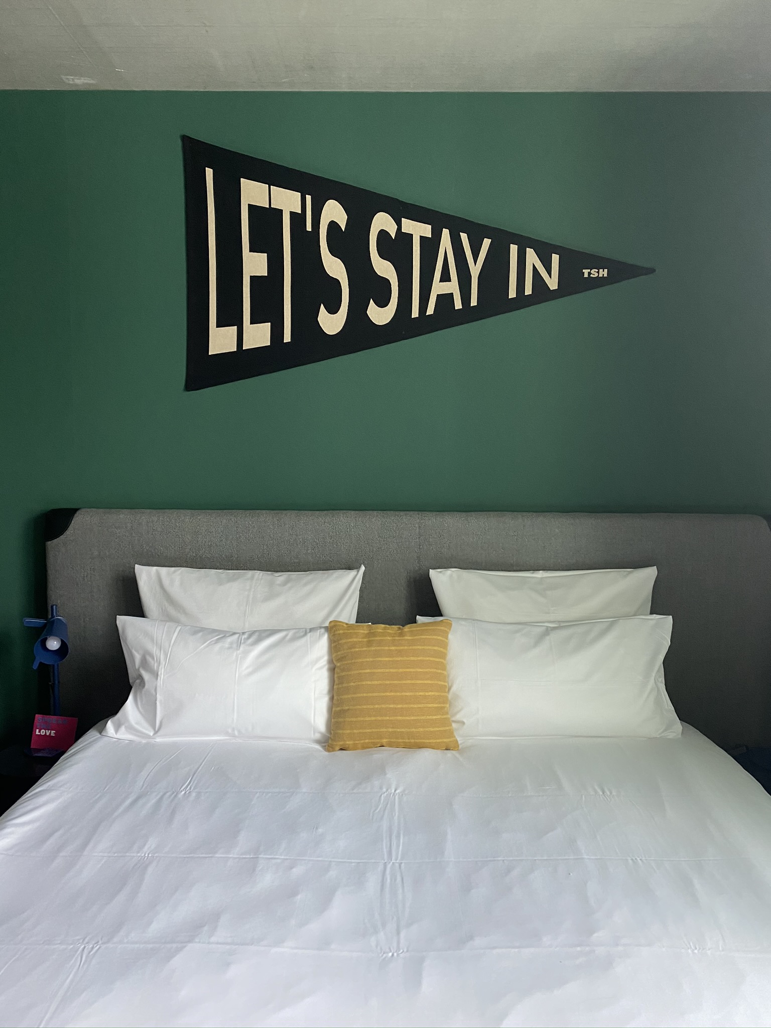 An der Wand über einem Bett steht "Lets stay in"