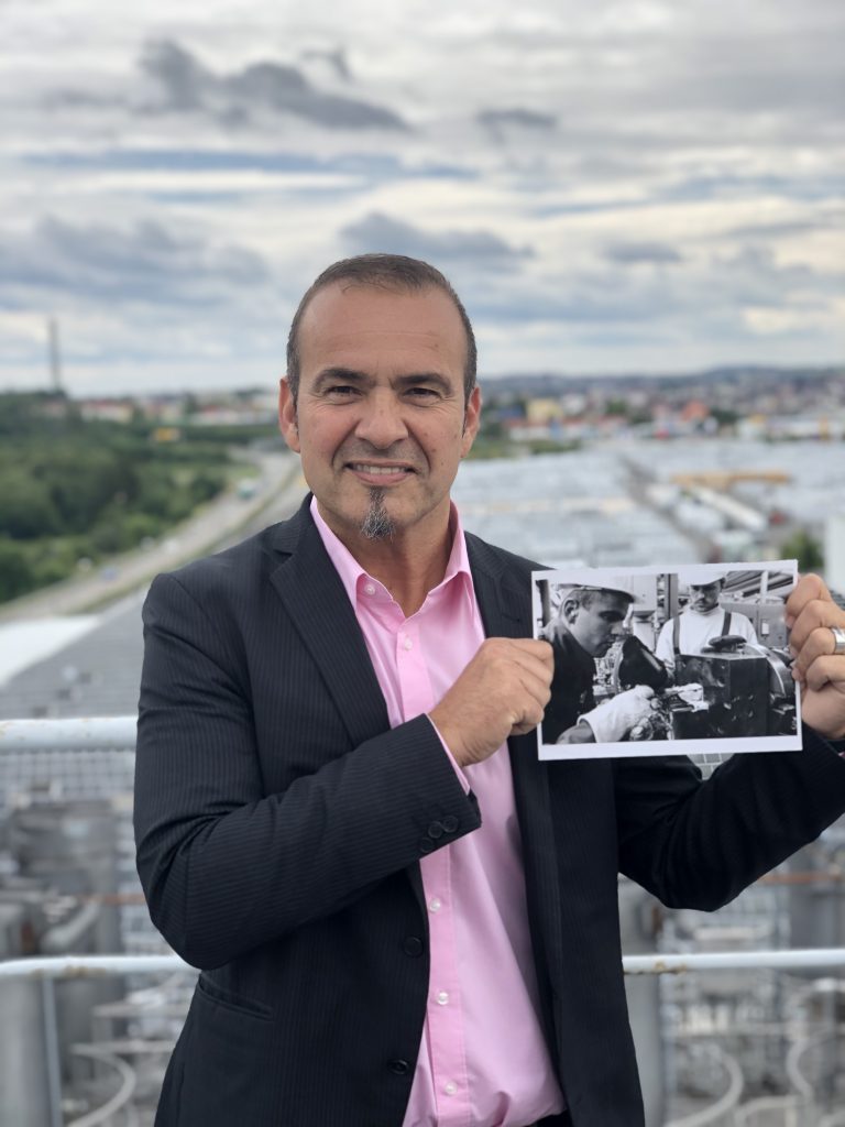 Christian Amling on the rooftop of profine holding a picture of him from the past.