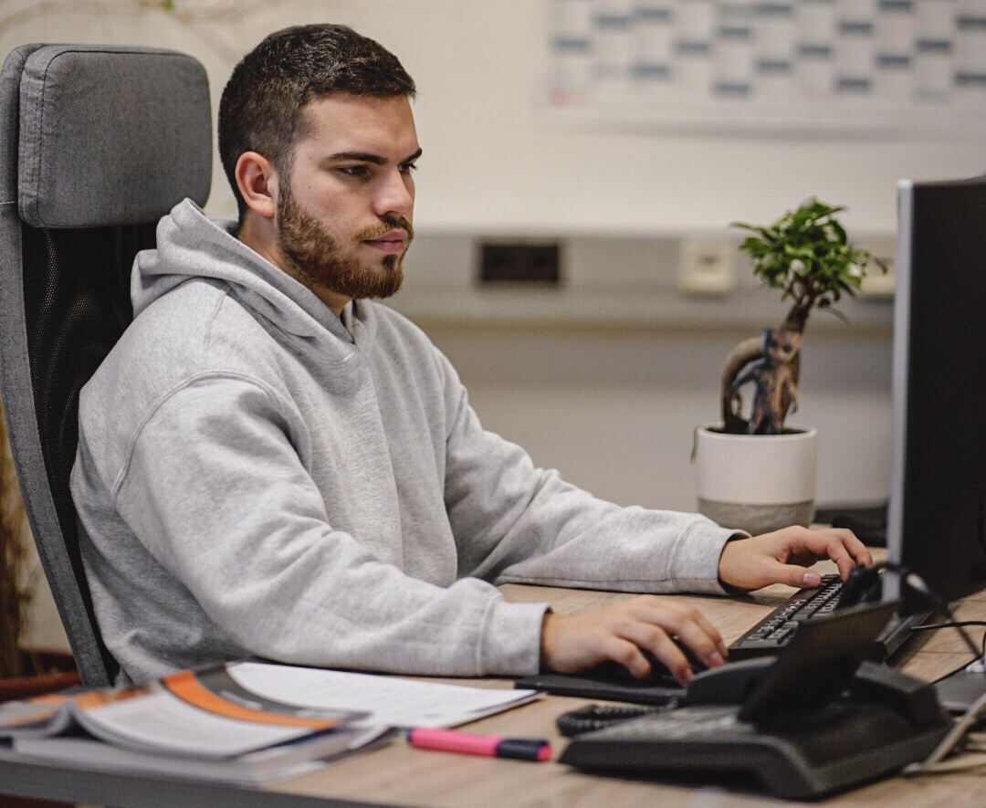 Unser Dualer Wirtschaftsinformatik Student Max sitzt an seinem PC-Arbeitsplatz.