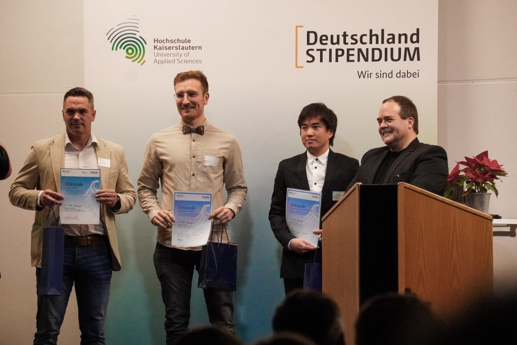 Andreas Langner übergibt das profine Stipendium an zwei Studenten der Hochschule Kaiserslautern.